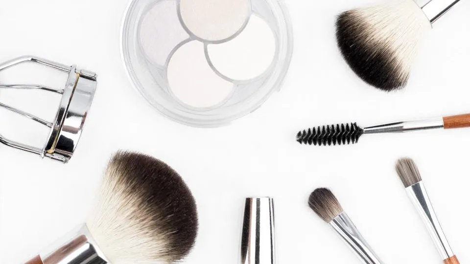 Weiche Make-up-Pinsel und eine Puderdose auf hellem Hintergrund